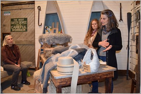  Behind a table of upholstery supplies is Anne in the background as Stphanie speaks about Gotland wool. Photo: Peggy Lundquist.